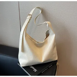 Detail of cream white leather crescent bag with soft pleats and gold metal buckle