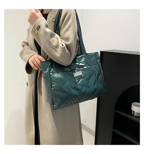 Detail of dark green quilted tote bag with metallic finish and fashion tag held by model