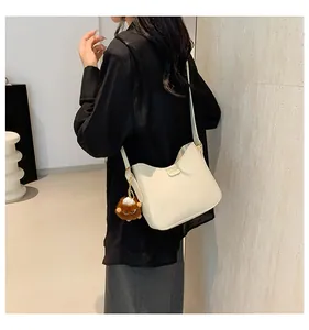 Detail of cream leather hobo bag featuring gold fashion plate and brown faux fur charm