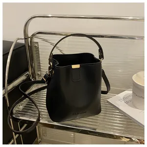 Détail du sac seau noir avec ferrures dorées et inscription fashion sur le cuir poli