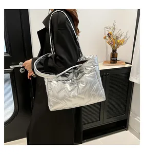 Close-up of silver quilted puffer tote bag with metallic finish and thick padded straps