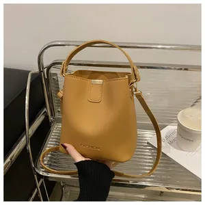 Vue détaillée du fermoir métallique et du logo embossé sur ce sac seau jaune tendance