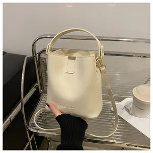 Vue détaillée du sac seau en cuir PU crème avec boucles dorées et lettrage fashion