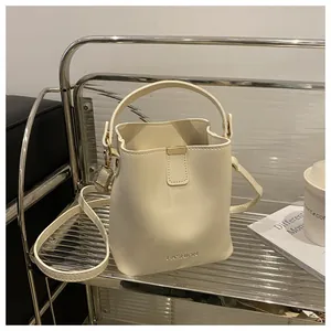 Détail du sac seau crème avec garniture dorée et texte mode sur étagère moderne