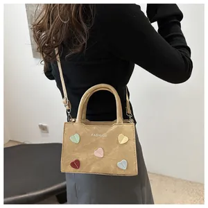 Detail of khaki crossbody mini bag with colorful heart patches and fashion print