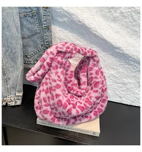 Détail d'un sac à main en peluche imprimé léopard rose sur un support noir avec un livre