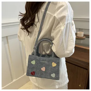 Detail of grey-blue textured handbag featuring colorful heart patches and fashion print