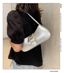 Borsa baguette argento metallizzato con fibbia dorata indossata a spalla per stile