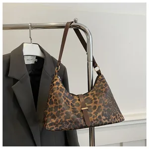 Détail d'un sac à bandoulière léopard avec sangle en cuir marron et garnitures dorées