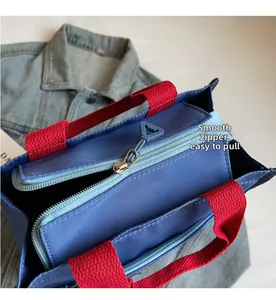 Close-up of smooth double zipper with triangular blue pulls on a navy canvas tote bag