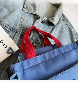 Close-up of waterproof nylon tote bag showing zipper detail and contrast red handles