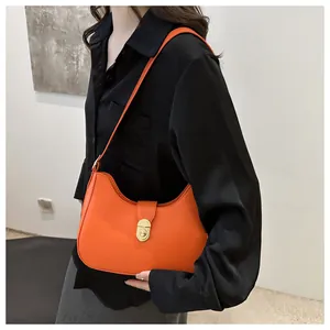Close-up of bright orange crescent underarm bag with gold twist lock and fine leather texture