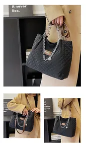 Detail der schwarzen gesteppten Shopper-Tasche mit Silberkette und braunem Lederetikett