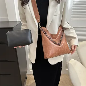 Detail of vintage brown shoulder bag with a matte texture, bold chain and black inner pouch