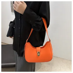 Close-up of bright orange hobo bag with a gold metal twist lock and stitching details