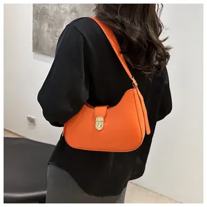 Close-up of bright orange crescent underarm bag with gold oval twist-lock hardware