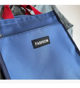 Close-up of blue nylon lunch bag featuring red handles and a black Fashion logo tag