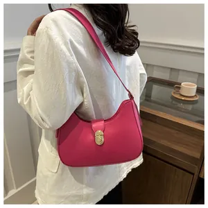 Detail view of pink leather crescent underarm bag featuring a golden oval metal buckle