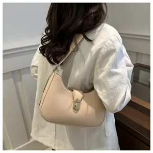 Close-up of beige hobo shoulder bag with a gold metal twist lock on a female model