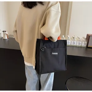 Detail of black waterproof lunch tote with orange straps and a minimalist fashion label