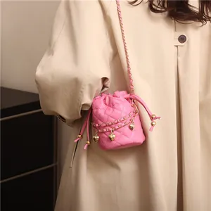 Pink quilted bucket bag with golden heart charms shown on a beige trench coat