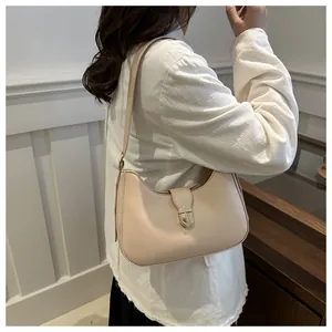 Detail view of a beige minimalist crescent hobo bag with a circular metal buckle