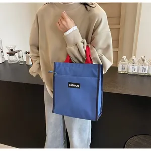 Blue waterproof lunch bag with red handles and Fashion label shown in use