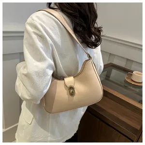 Detail showing the creamy beige crescent hobo bag with its gold oval metal turn-lock closure