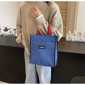 Close-up of blue canvas lunch bag with red handles and front pocket in a cafe setting