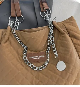 Detailansicht der braun gesteppten Tragetasche mit Rautenmuster und Kettengriff-Details