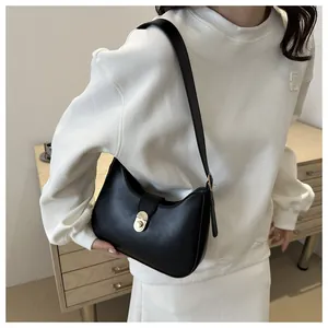 Detail view of black crescent hobo bag with gold cylindrical twist lock on model shoulder