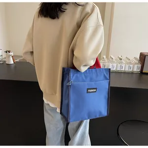 Detail of blue canvas tote bag with red handles and zip pocket for daily commuting