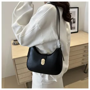 Close-up of minimalist black leather crescent shoulder bag with golden metallic clasp