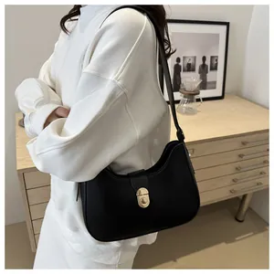 Close-up of a black crescent shoulder bag with golden metallic clasp on model