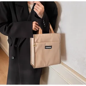 Detail of a beige waterproof lunch bag with a fashion logo and zipper front pocket