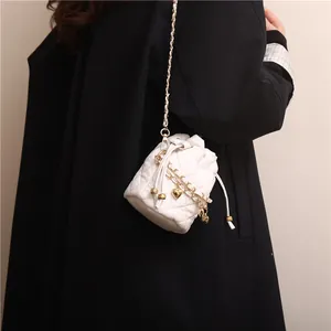 Chic white quilted bucket bag with gold chain strap and heart pendant shown on model