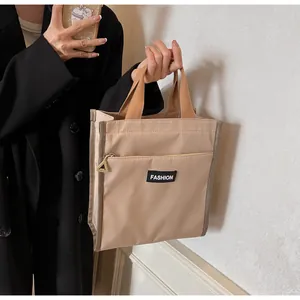 Close-up of beige waterproof lunch bag featuring a fashion tag and triangle zipper detail