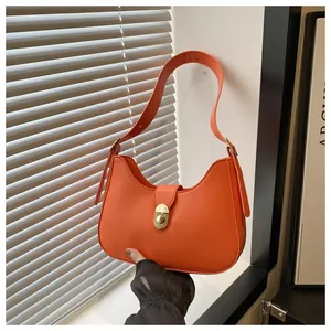 Detail of an orange leather hobo bag with a gold metal twist lock and adjustable strap