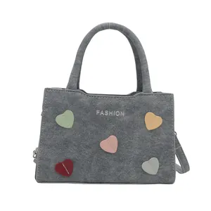 Gray textured handbag with colorful stitched heart patches and adjustable shoulder strap