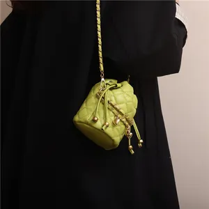 Detail of neon green quilted bucket bag with chain strap and gold heart pendant