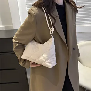 Close-up of beige quilted hobo bag with large diamond stitching and knot handle detail