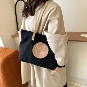 Minimalist black canvas tote bag with brown leather straps and OK YF logo patch
