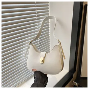Detail of white hobo bag with a golden turn-lock clasp and slim adjustable shoulder strap