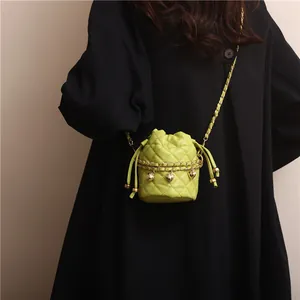 Detail of neon green quilted bucket bag with gold chain and heart charm on black coat