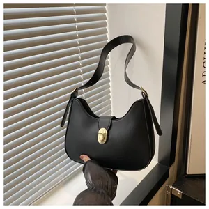 Detail of a matte black crescent hobo bag with gold twist lock and adjustable shoulder strap
