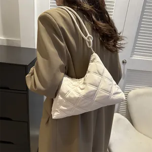 Quilted beige underarm bag with knotted shoulder strap detail shown on model