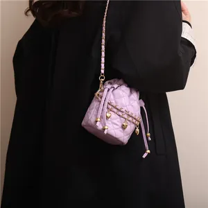 Detail of light purple quilted bucket bag with gold heart charms and chain strap
