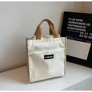 Detail of cream canvas lunch bag with front zipper pocket and brown woven handles