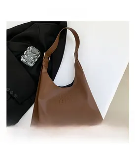 Detail of a brown matte leather bag with His His embossed logo and wide shoulder strap