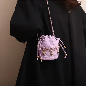 Detail of purple quilted bucket bag with golden heart charms and chain strap